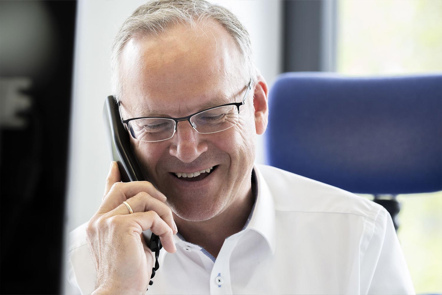 Ein Mann im Hemd lächelt am Telefon